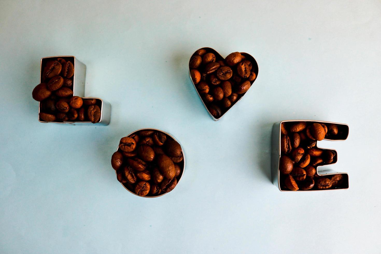 hermosa textura con la palabra amor para la inscripción del día de San Valentín hecha de granos de café arábica aromáticos naturales tostados seleccionados, espacio de copia robusta, puesta plana, fondo azul foto