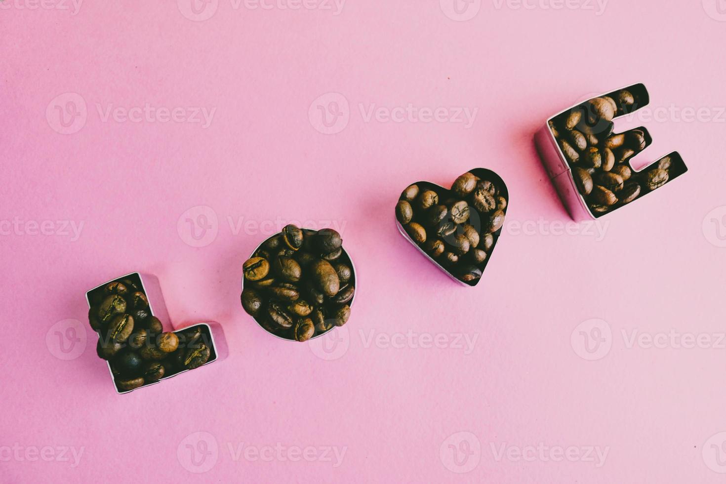 hermosa textura con la palabra amor para la inscripción del día de San Valentín hecha de granos de café arábica aromáticos naturales tostados seleccionados, espacio de copia robusta, puesta plana, fondo púrpura rosa foto