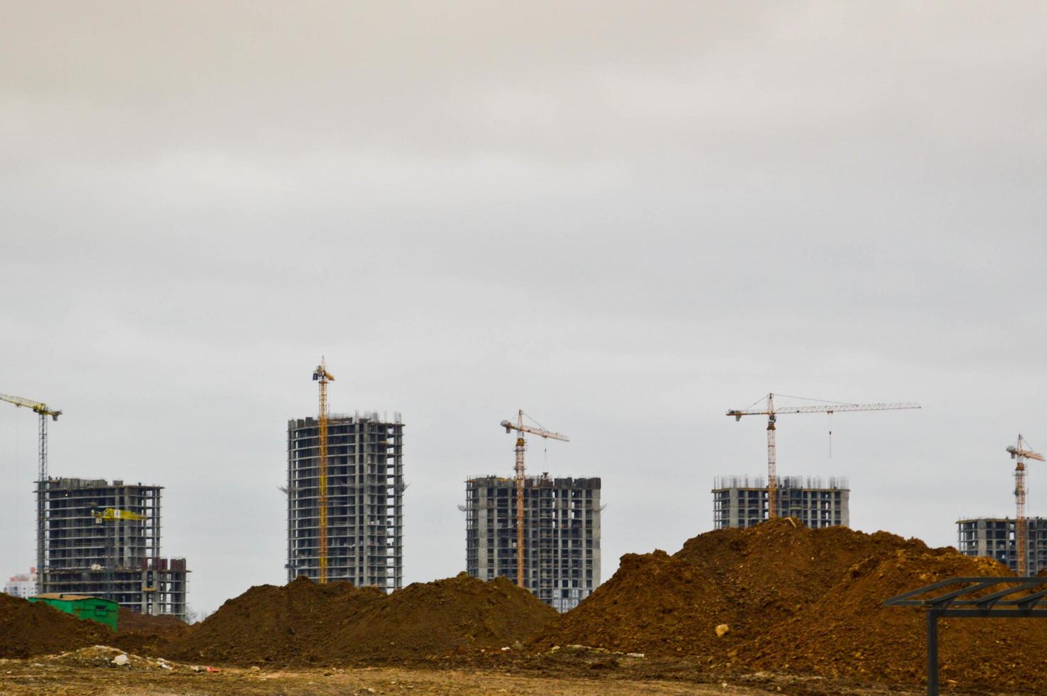 Construction of a new microdistrict with high houses, new buildings with developed infrastructure with the help of large industrial cranes and professional construction equipment in a big city photo