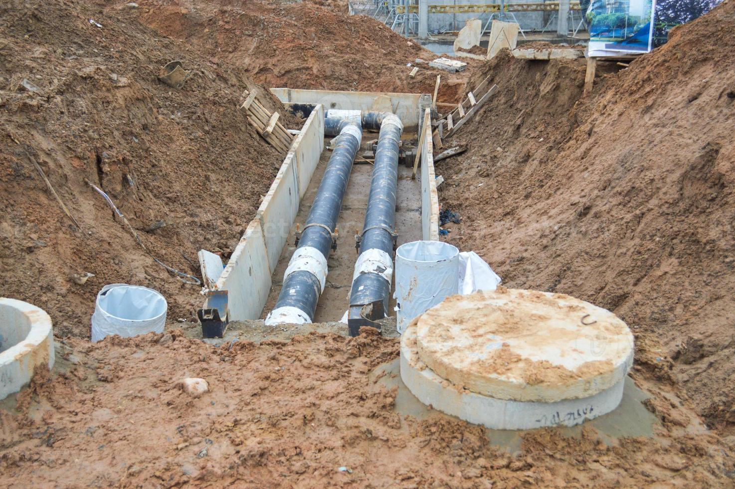 grandes tuberías de agua de metal negro y plástico para agua fría y caliente en un lugar de construcción durante una reparación en un nuevo barrio bajo tierra foto