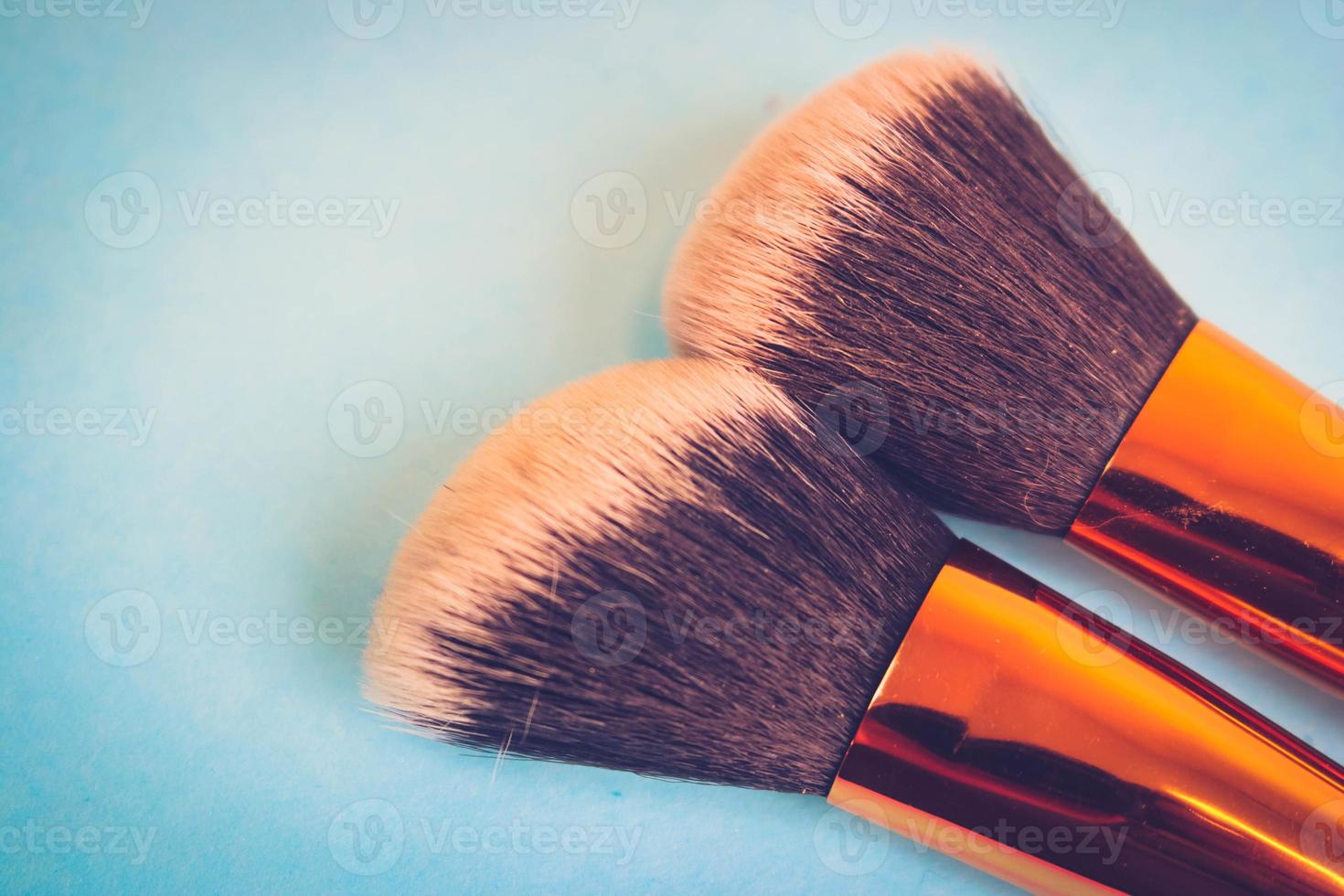 A set of beautiful different soft brushes for make-up from natural nap for beauty targeting and applying a tonal foundation in a stand and copy space on a blue background photo