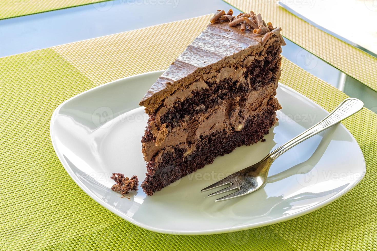 a delicate piece of chocolate cake, torte on a white plate with a fork photo
