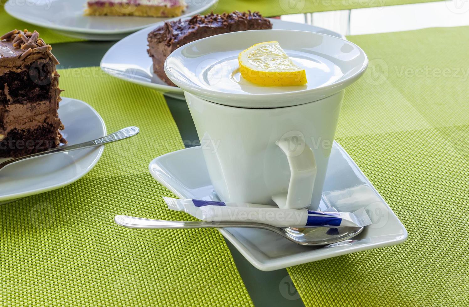 taza de té de porcelana blanca con limón, azúcar, cuchara sobre una mesa en la cafetería. foto