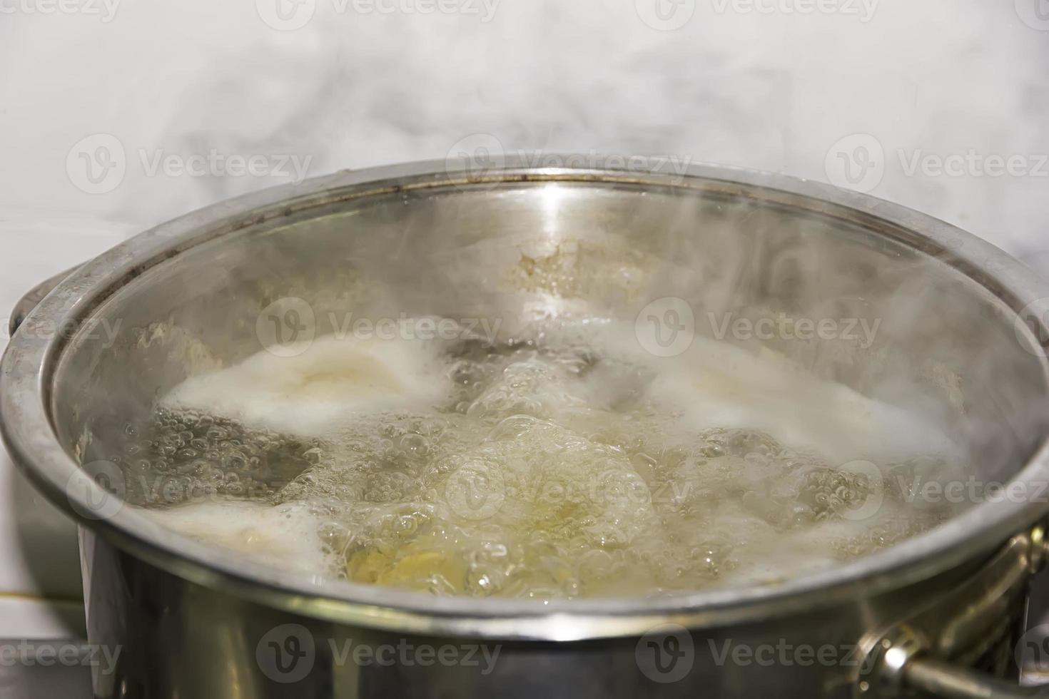Boiling water in a pan with potatoes in the kitchen with smoke. Close up photo