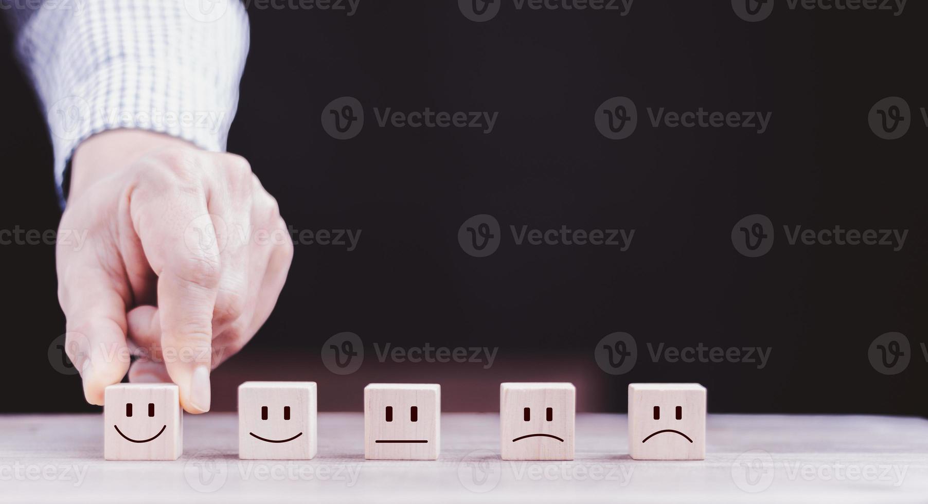 best excellent business services rating customer experience. Satisfaction survey concept. Hand of a businessman chooses a smiley face on wood block cube. photo