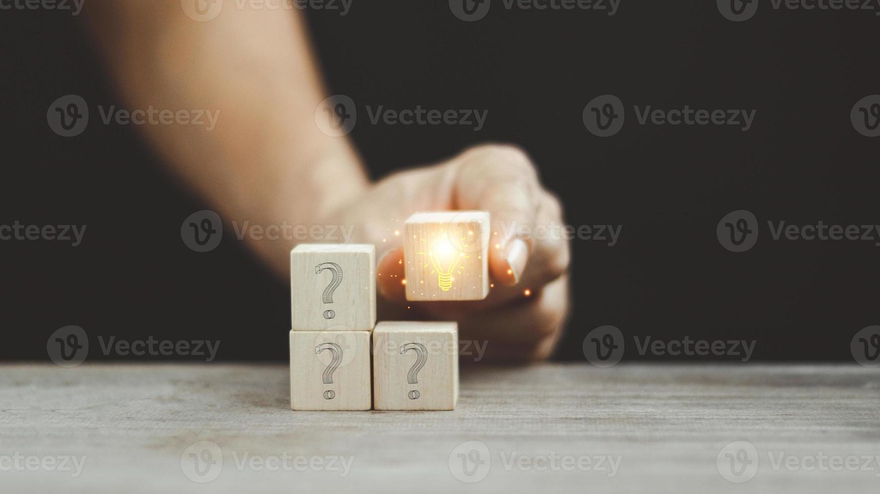 Concept of problem solving, creativity, idea or innovation. Male hand places a wooden cube with hand drawn light bulb next to the cubes with question marks. photo