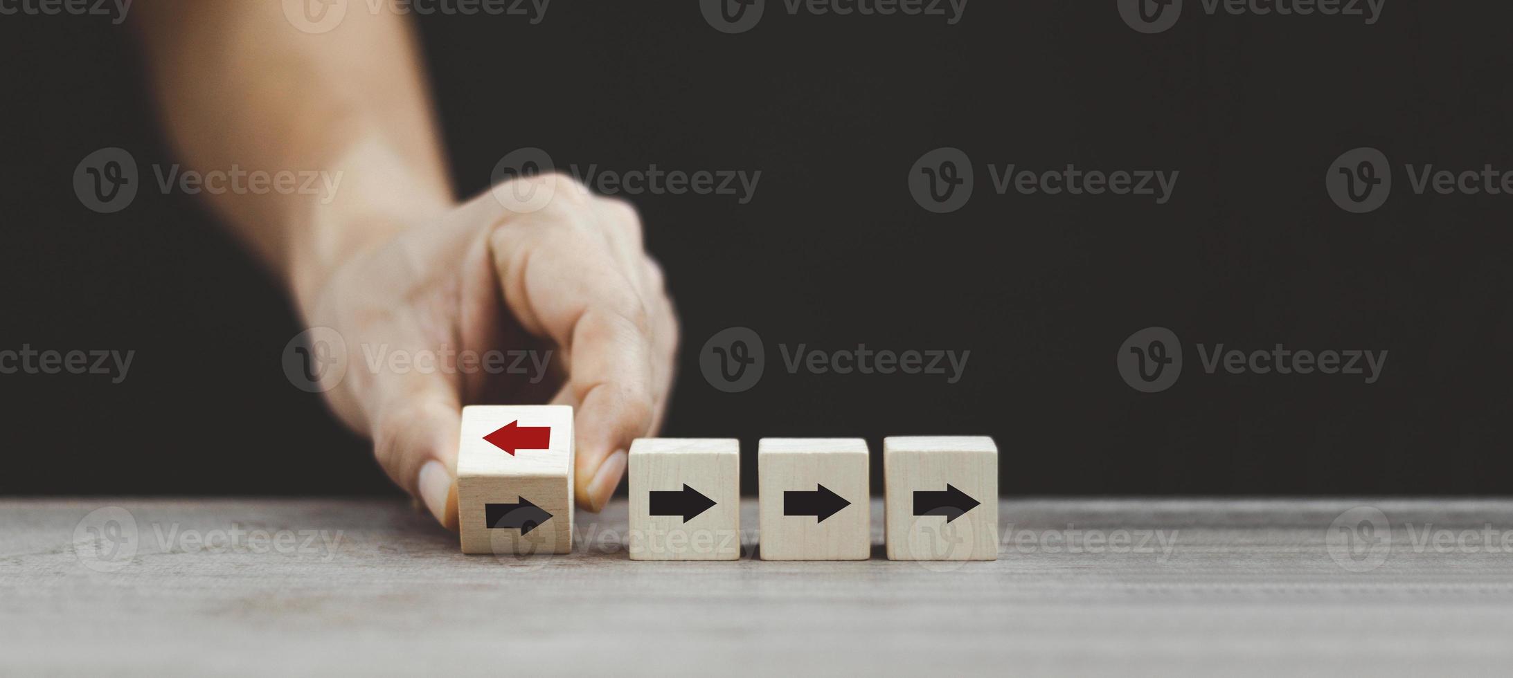 Hand flipping wooden cube block arrow from change left to right for business disruption and different thinking idea. photo