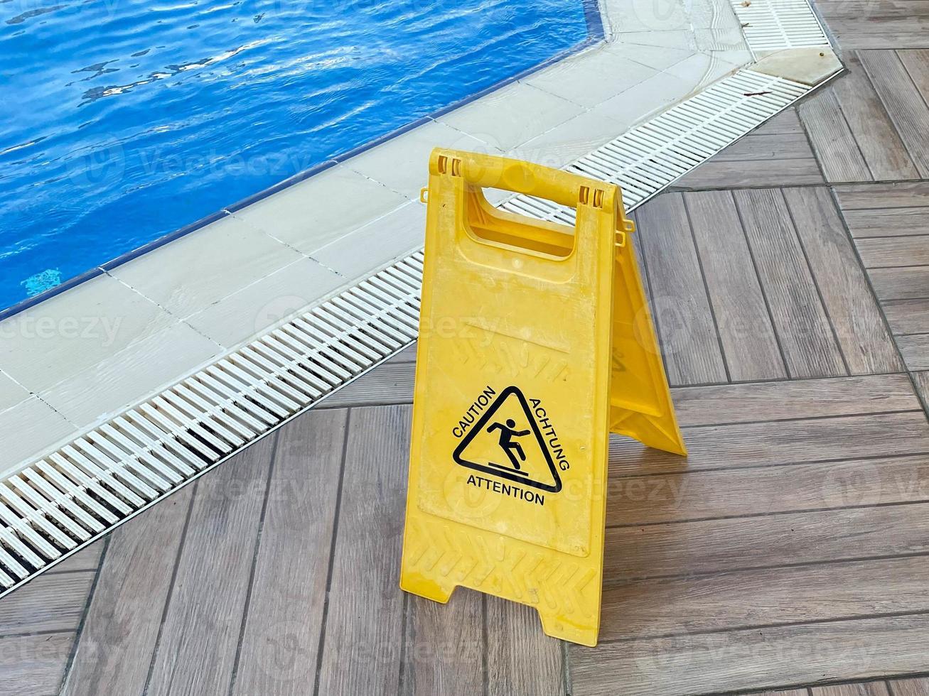 suelo mojado con letrero amarillo cerca de la piscina con agua para nadar y relajarse en un hotel en un cálido complejo tropical del este del país foto