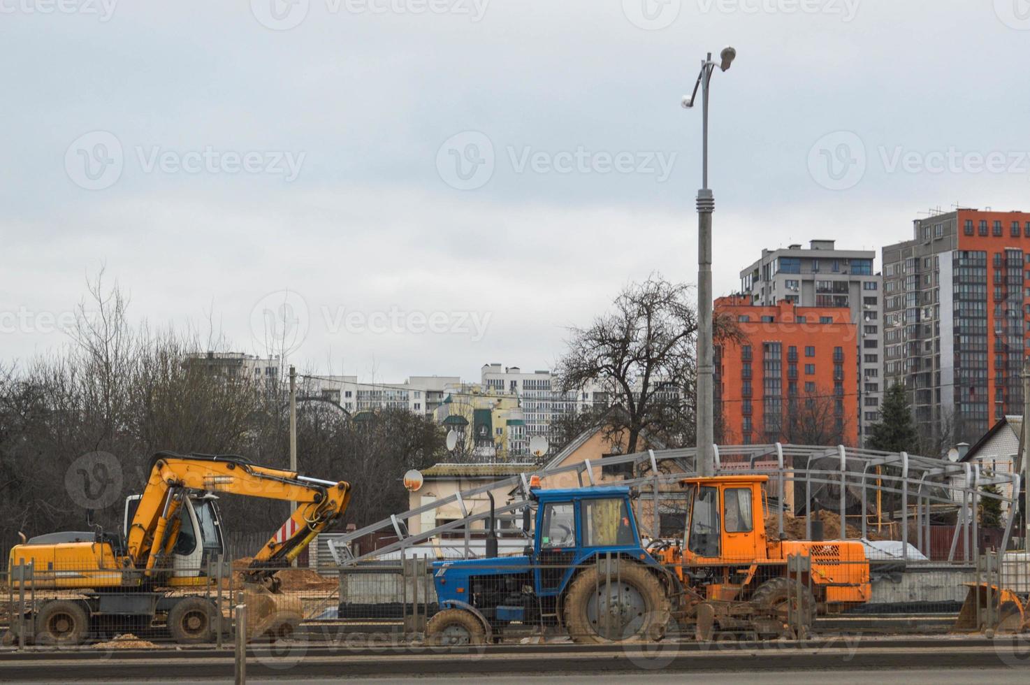 Many powerful industrial heavy specialized construction equipment of tractor excavators and bulldozers make road repairs during the construction of a new micro-district in a big city photo