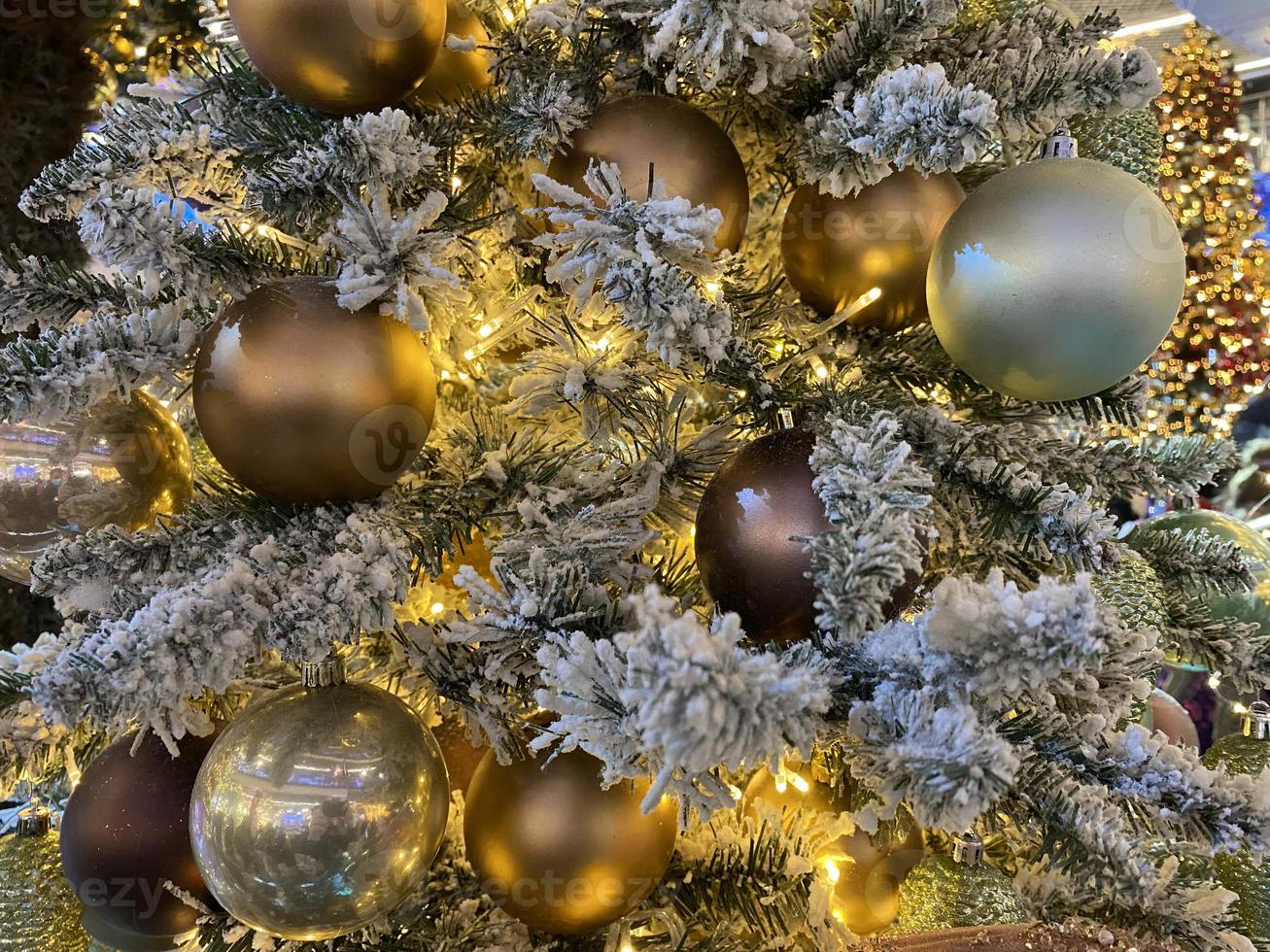 Green branches of a fluffy Christmas festive New Year tree with toys in balls and bright glowing light bulbs and garlands, background photo