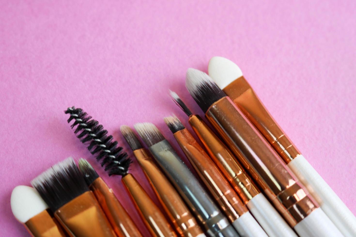 A set of beautiful different soft brushes for make-up from natural nap for beauty targeting and applying a tonal foundation in a stand and copy space on a pink, purple background photo