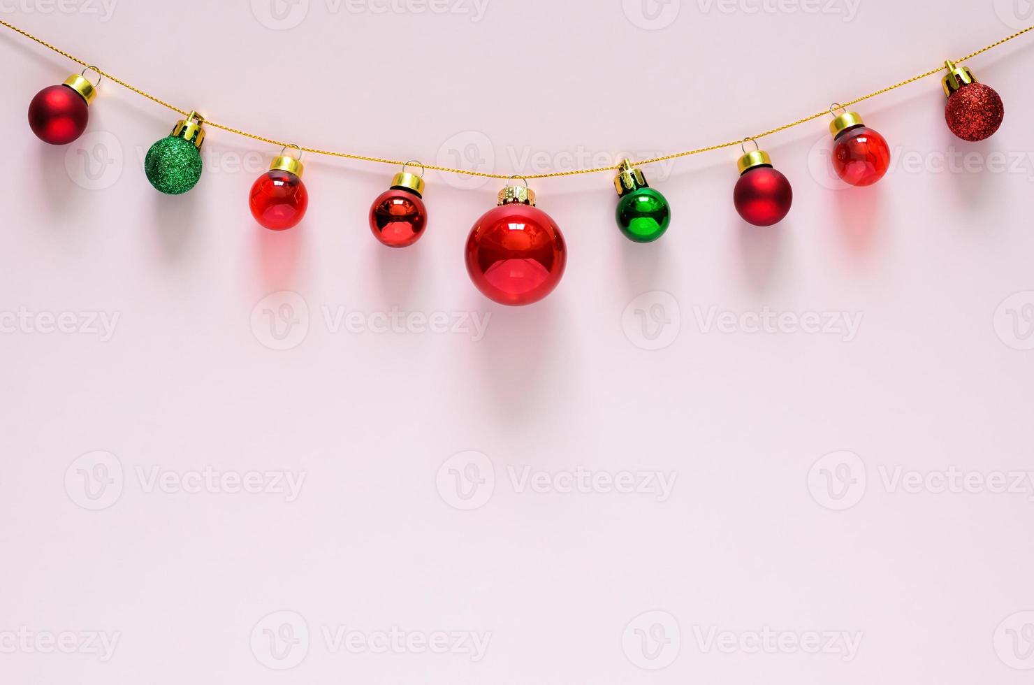 Colorful Christmas baubles ornament hanging on top with pink background. Minimal holiday concept. photo
