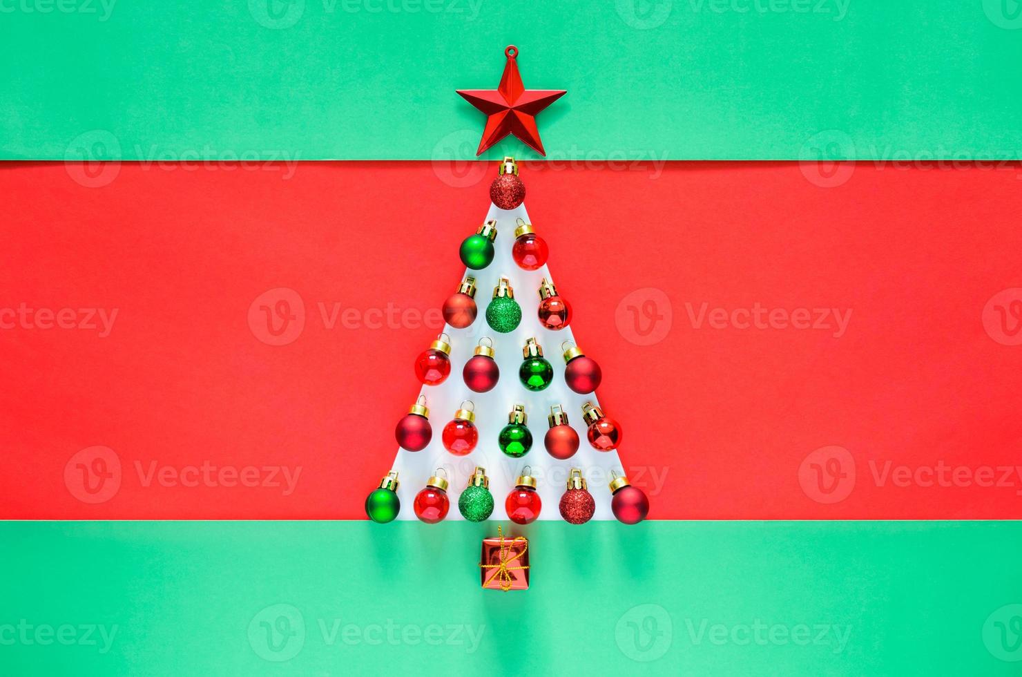Christmas baubles ornament decorated as Christmas tree on red and green background. Minimal holiday concept. photo