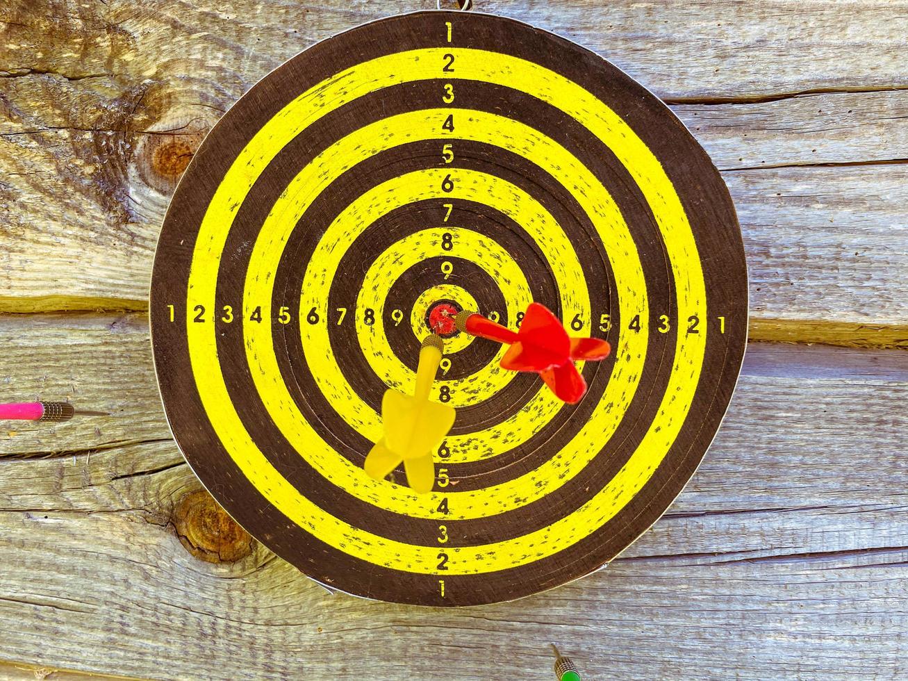 active play. throwing darts. darts outdoors. round field with black and yellow markings. inside bright darts in the center, hitting the center of the circle photo