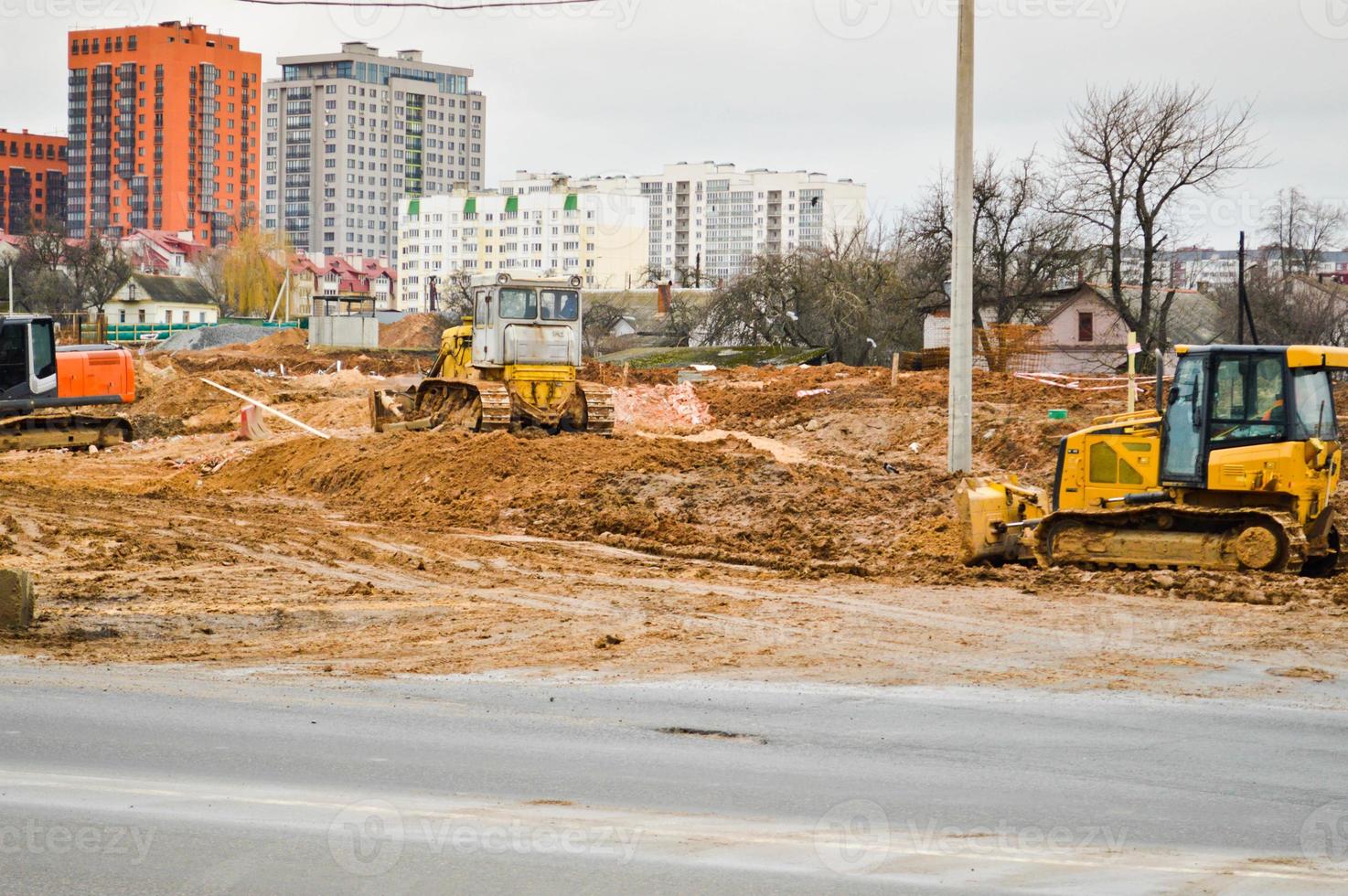 Muchos potentes equipos industriales pesados de construcción especializados de excavadoras de tractores y excavadoras reparan carreteras durante la construcción de un nuevo microdistrito en una gran ciudad foto