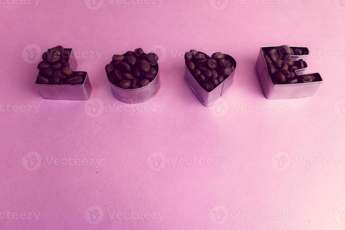 hermosa textura con la palabra amor para la inscripción del día de San Valentín hecha de granos de café arábica aromáticos naturales tostados seleccionados, espacio de copia robusta, puesta plana, fondo púrpura rosa foto