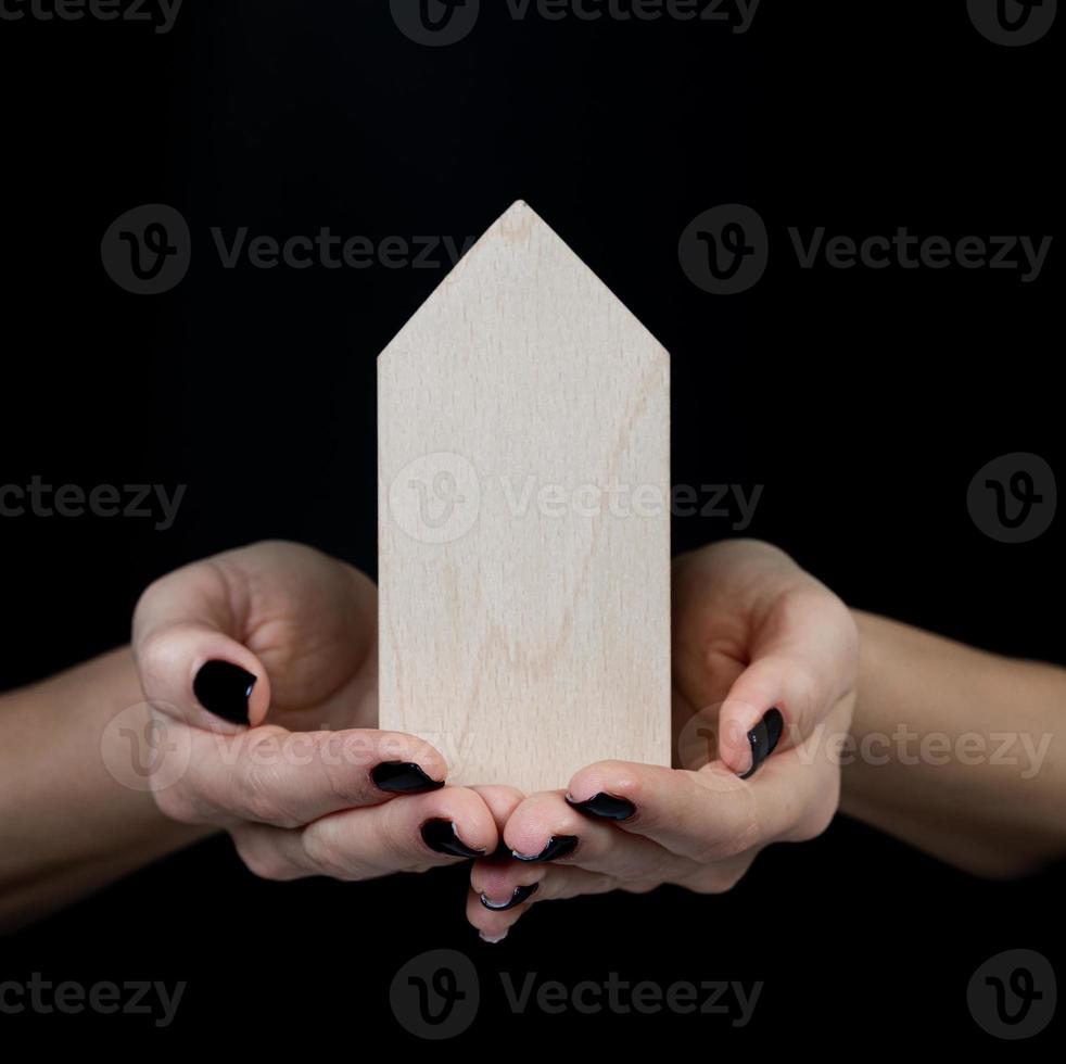 Houses symbol Hand with metal key on black background. Real estate, insurance concept, mortgage, buy sell house, realtor concept, little cars, trees photo