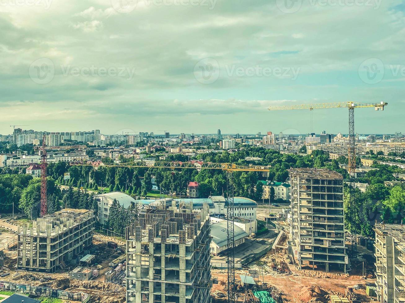 construction of multi-storey buildings in the city center. tall houses made of concrete blocks and slabs. heavy, yellow, metal crane lifts building material up photo