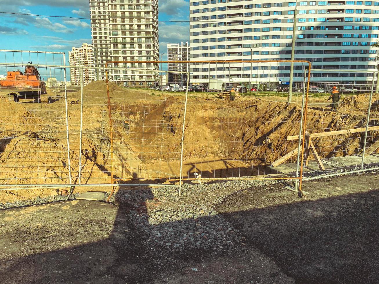 construction of a new microdistrict in the city center. a moat was dug out of sand for laying communications, water, cables with electricity. sand behind the fence photo