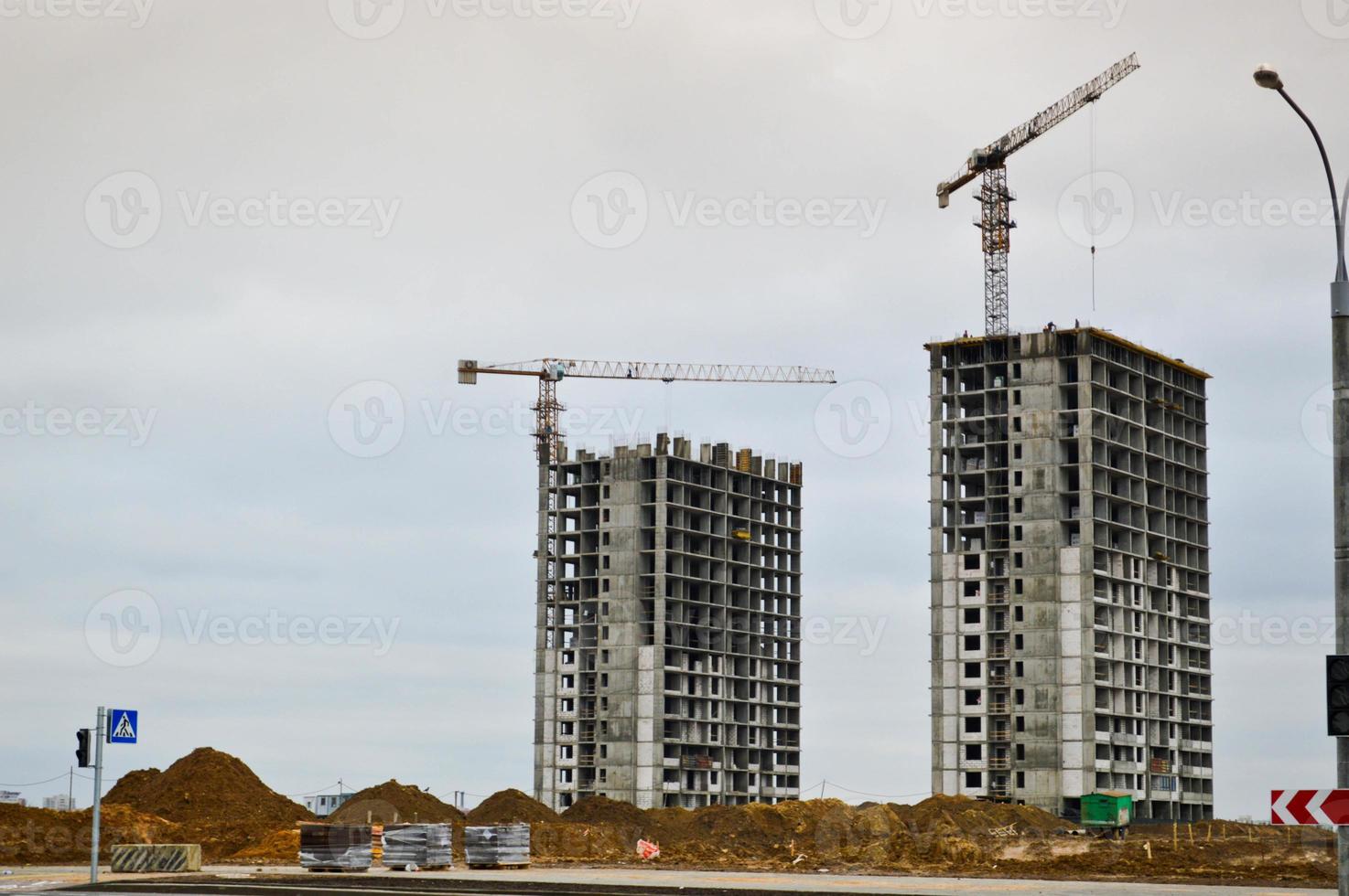 Construction of a new microdistrict with high houses, new buildings with developed infrastructure with the help of large industrial cranes and professional construction equipment in a big city photo