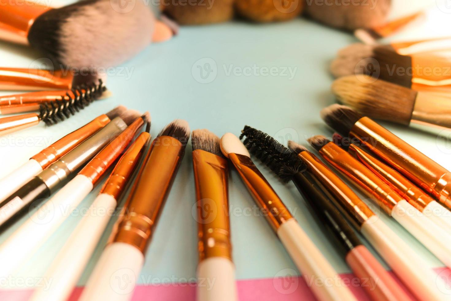 A frame from a set of beautiful different soft makeup brushes from natural lint for targeting beauty and applying a tonal foundation in a stand and copy space on a blue background photo