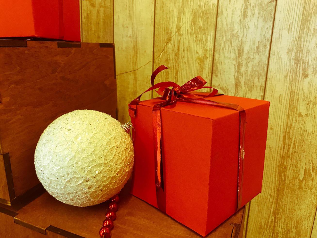 A small cute white Christmas tree decoration, a ball and New Year's festive decoration and a red gift box photo