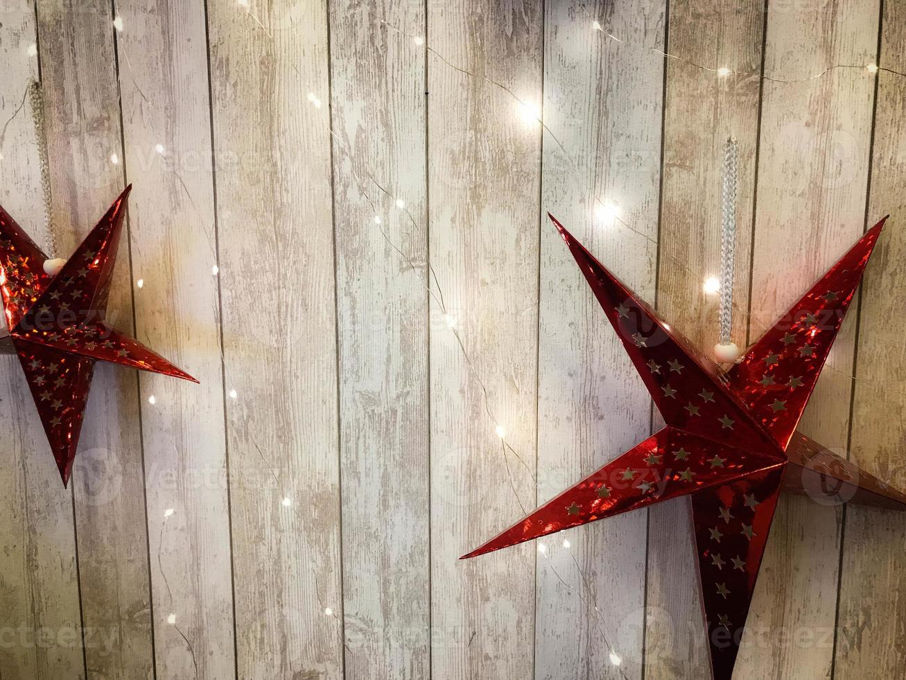 grandes y lindas estrellas rojas navideñas, navidad, decoración de año nuevo contra el fondo de gerlyand brillante sobre tablas verticales de madera con costuras foto