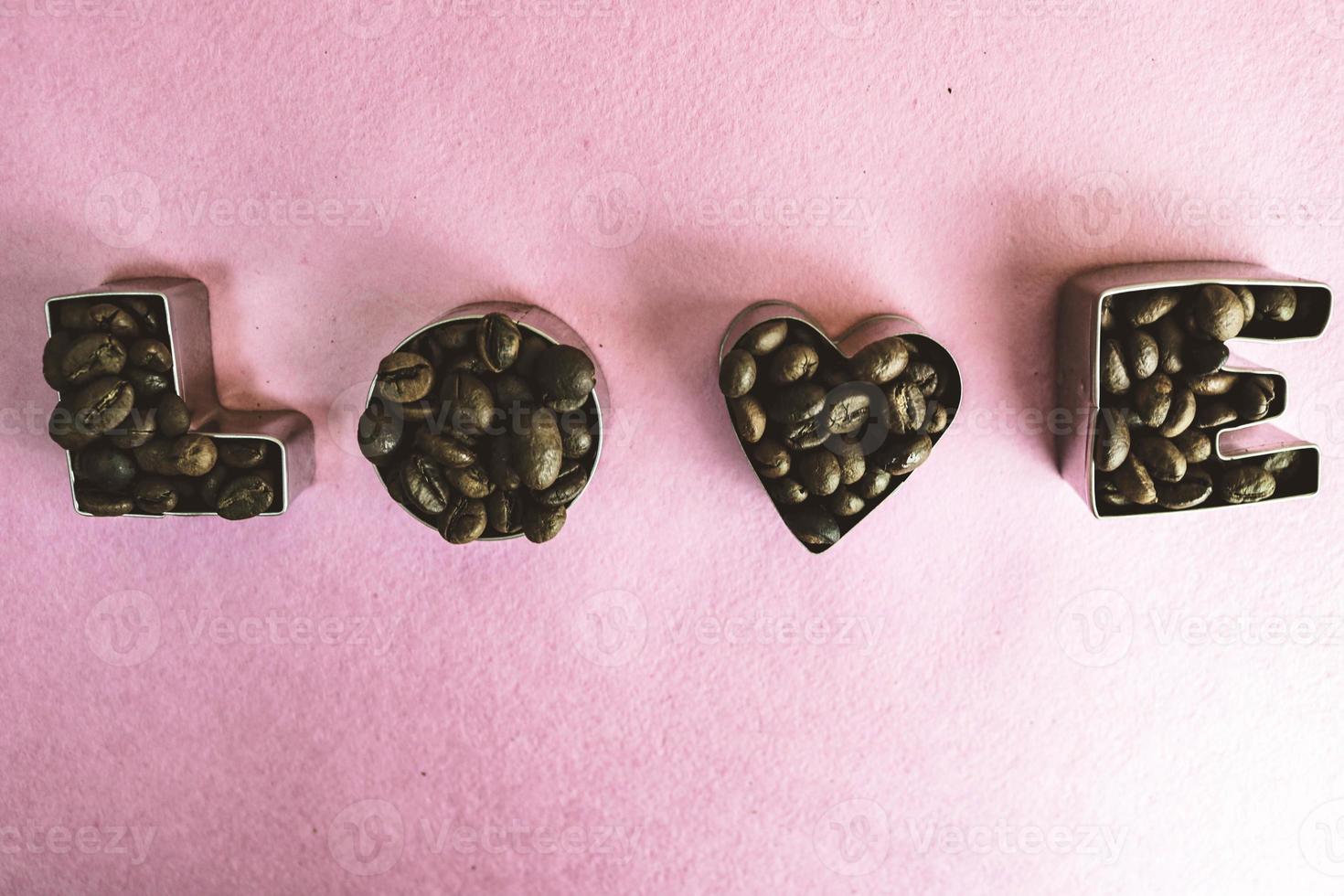 Beautiful texture with the word love for valentine's day inscription made from roasted selected brown natural aromatic Arabica coffee beans, robusta Copy space, flat lay, pink purple background photo