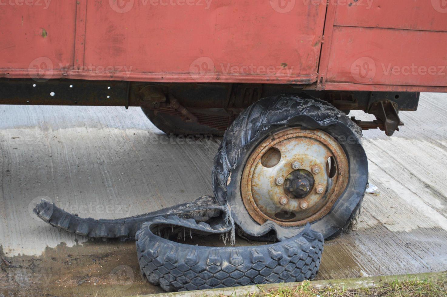 A large black rusty rubber wheel with a torn worn out broken bad old full of tires insecure tire photo