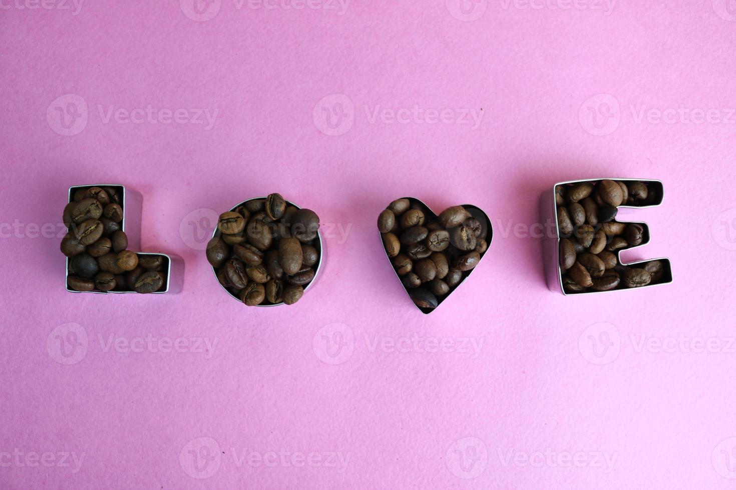 Beautiful texture with the word love for valentine's day inscription made from roasted selected brown natural aromatic Arabica coffee beans, robusta Copy space, flat lay, pink purple background photo