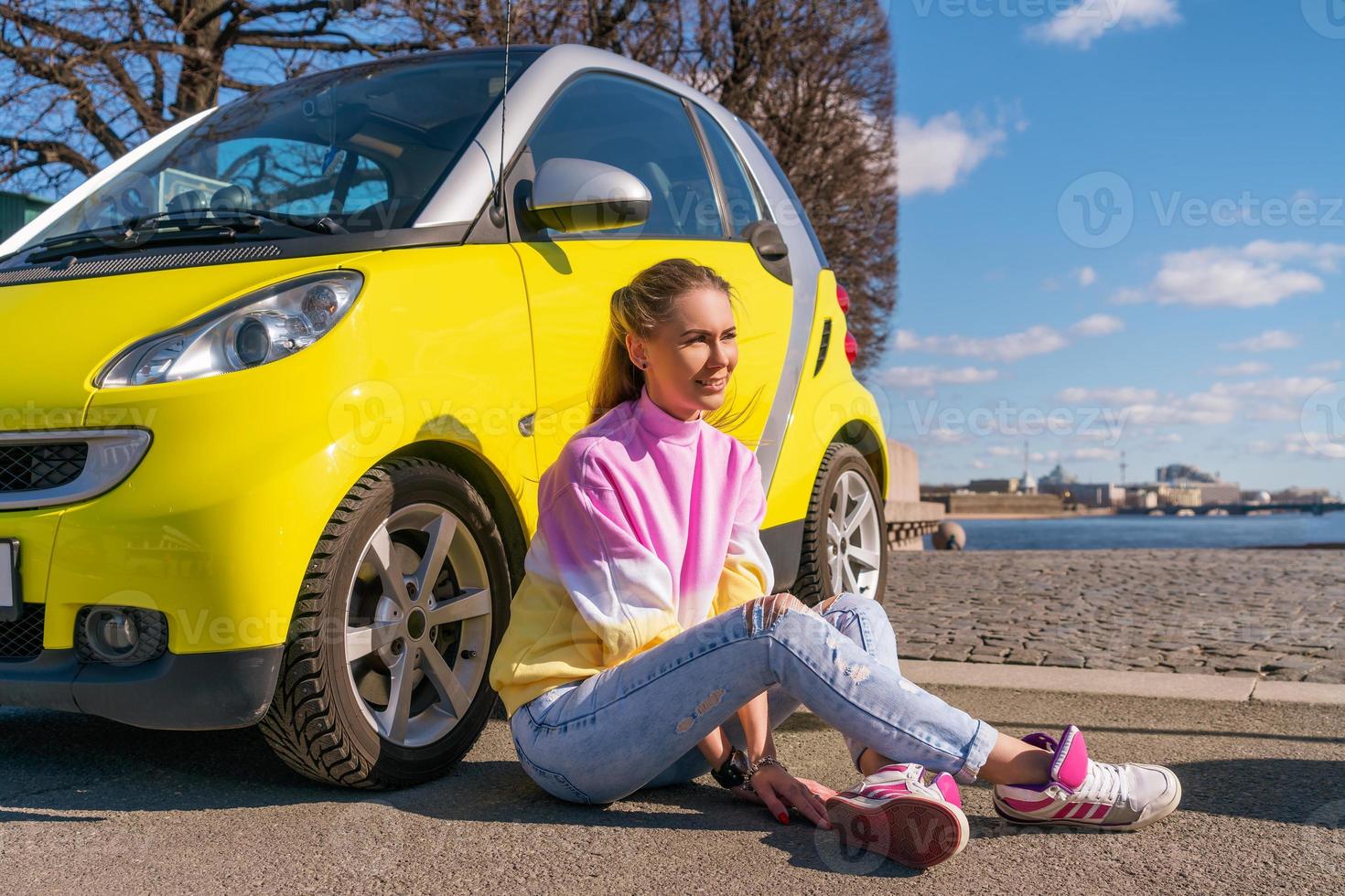 happy woman near a yellow car in the city photo