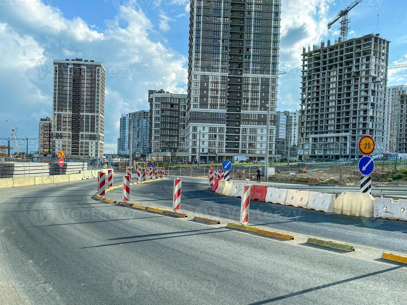 construction of a new microdistrict in the city center. tall, glass houses next to a gray concrete road. laying communications in the city photo