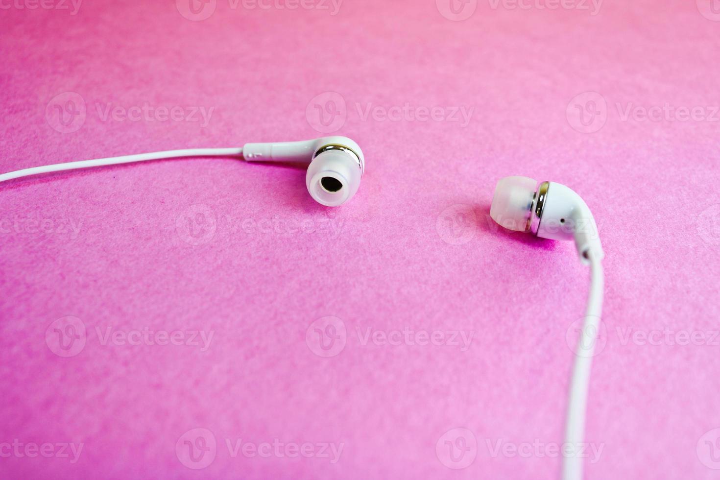 Beautiful modern digital plastic vacuum white headphones with wires for listening to music on a purple pink background. Copy space photo
