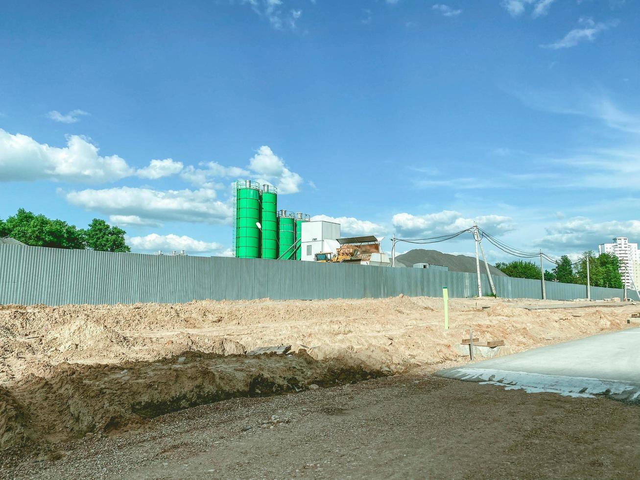 construction of a new neighborhood in the city. green concrete junction. production of material for building houses. behind a high fence lies asphalt and building materials photo