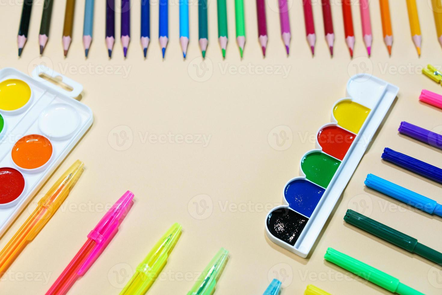 Colored pencils and markers with pens and paint on paper background with copy photo