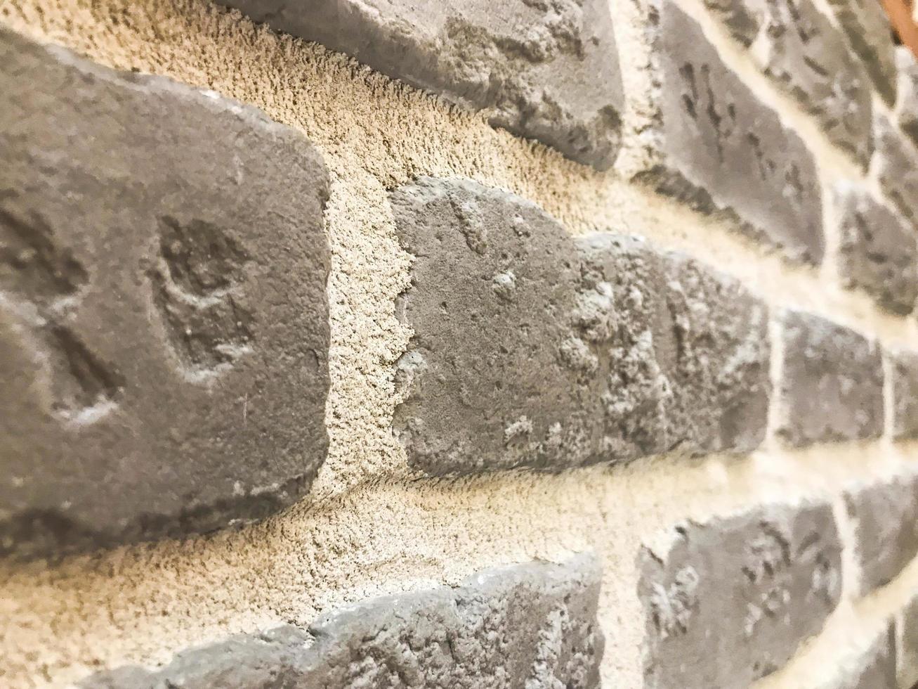 Beautiful texture of a decorative stone wall at an angle of building gray textured relief brick, stone of plaster with seams. The background photo