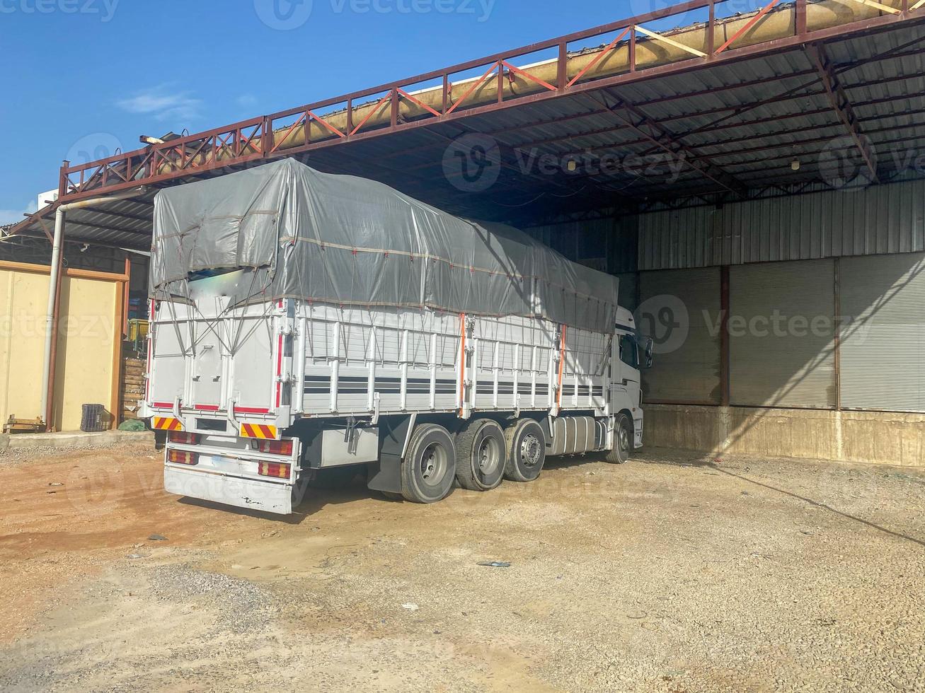 A large white powerful truck with an awning and a trailer is parked to unload cargo photo