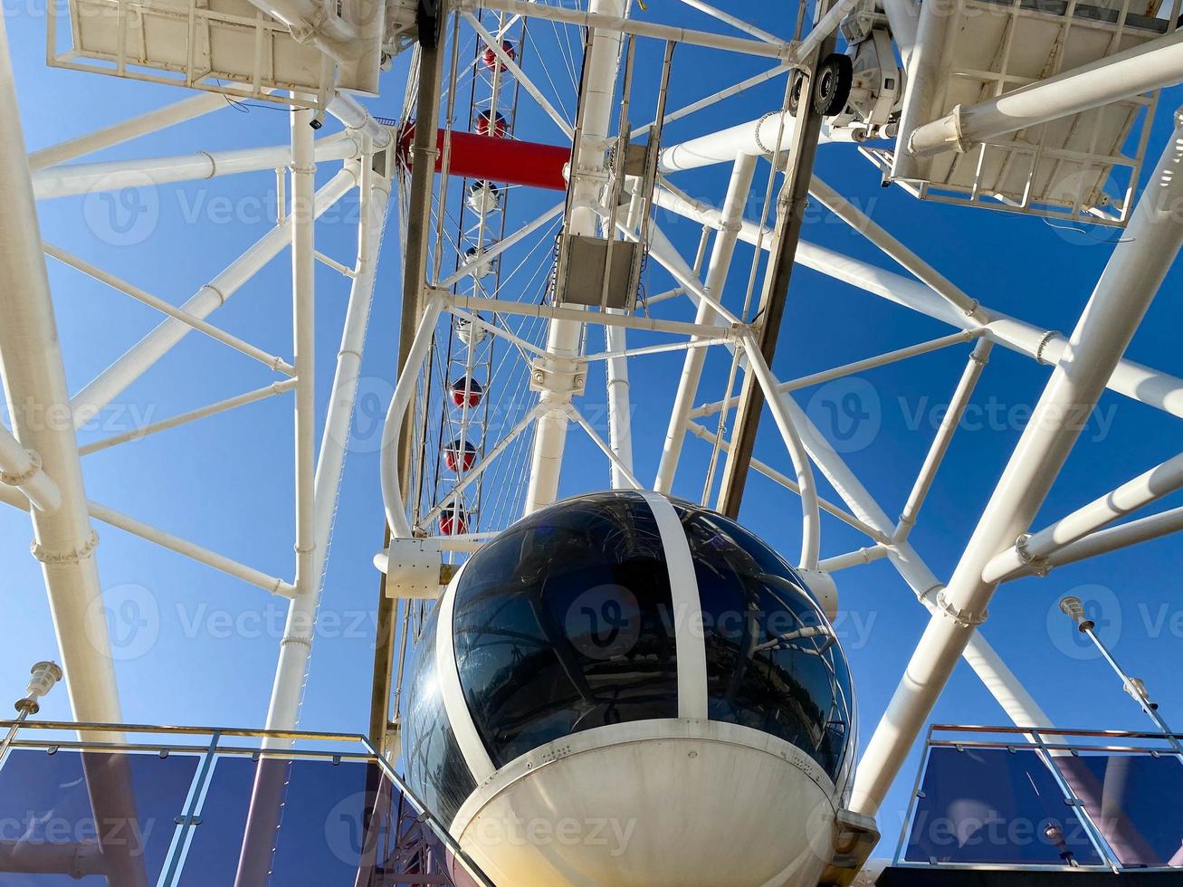 amusement park. Ferris wheel made of white metal. On the wheel there are large cabins for skiing white tourists. cozy cabin for people to ride photo