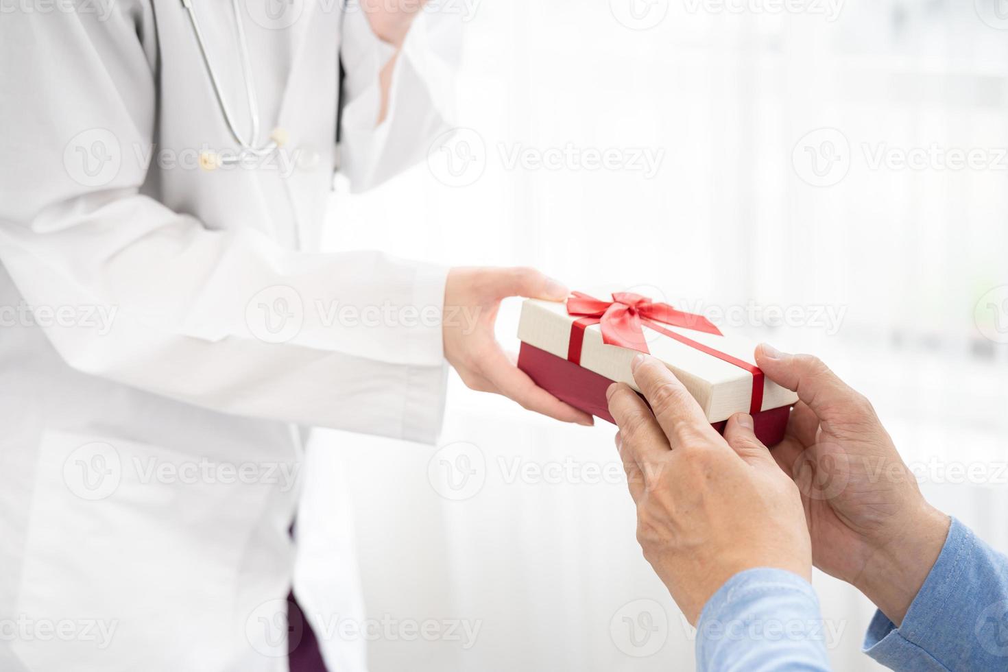 Doctor to senior old elderly people. Medical health care. senior's hand receives a gift box from doctor. photo