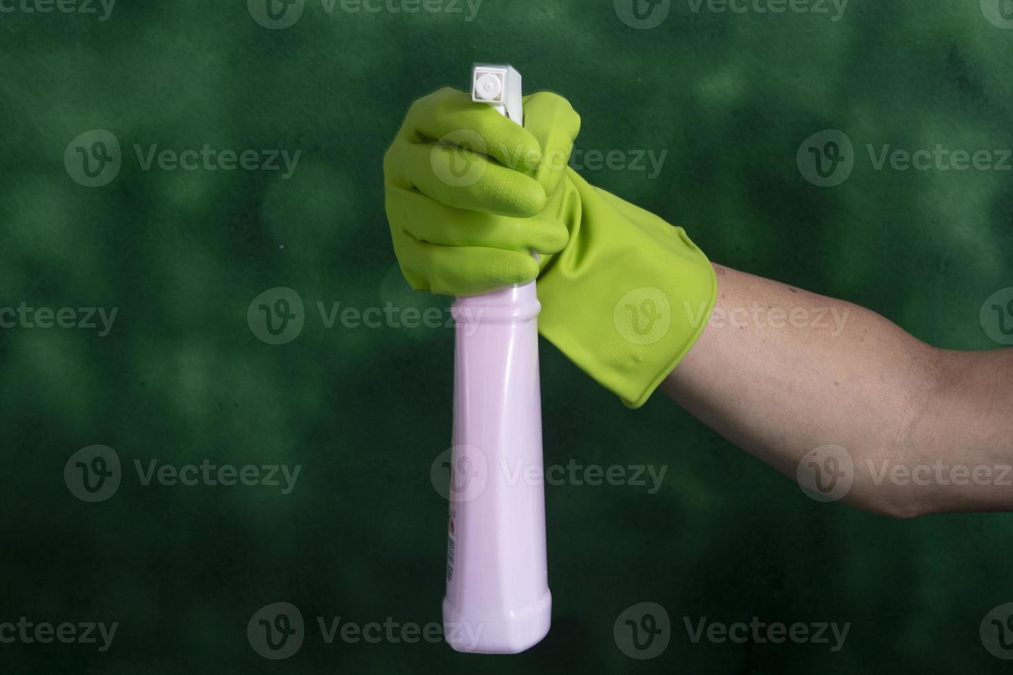 hand with protective glove holding packaging of cleaning products used for home hygiene photo