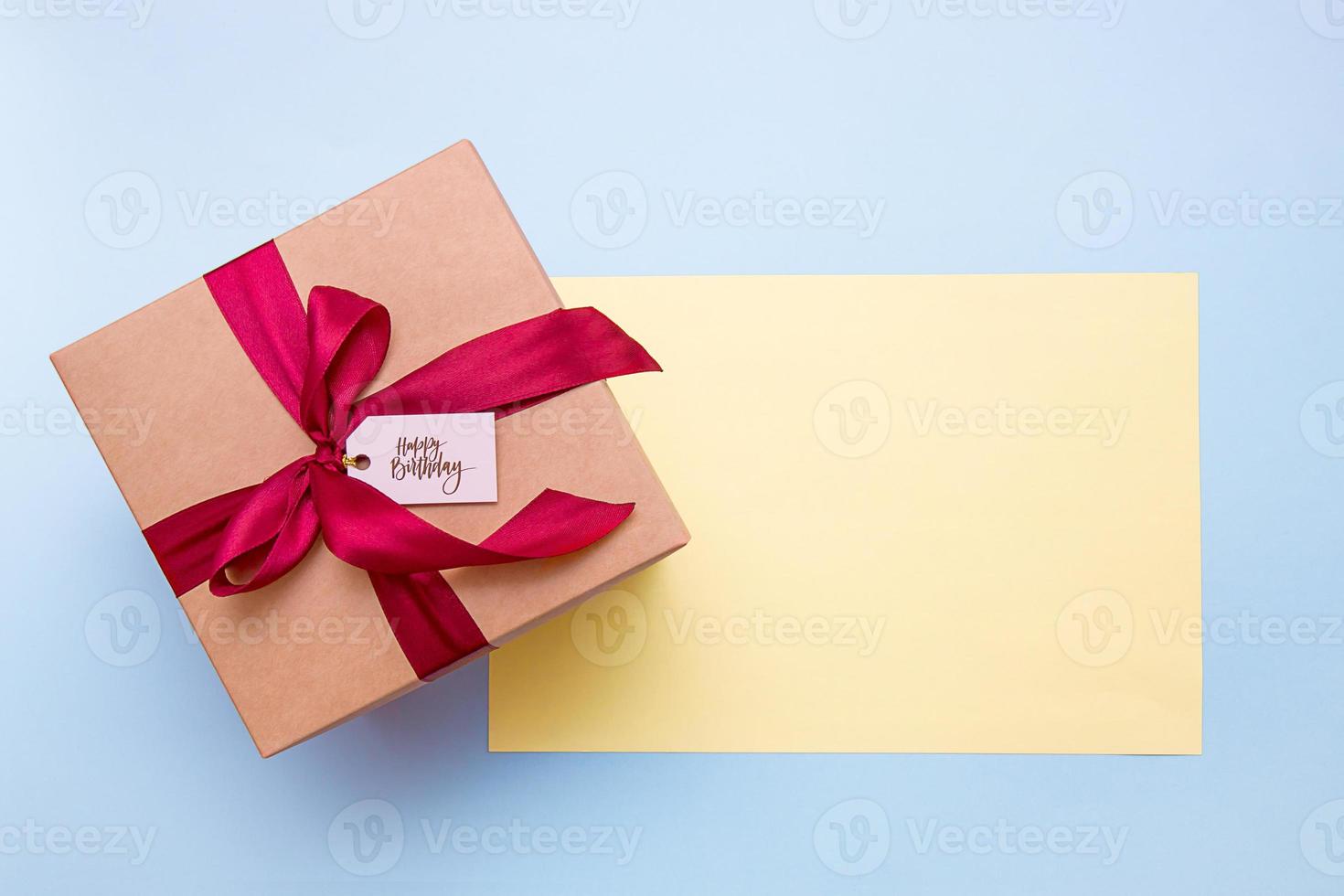 gift box with satin ribbon and happy birthday lettering on blue background with copy space photo