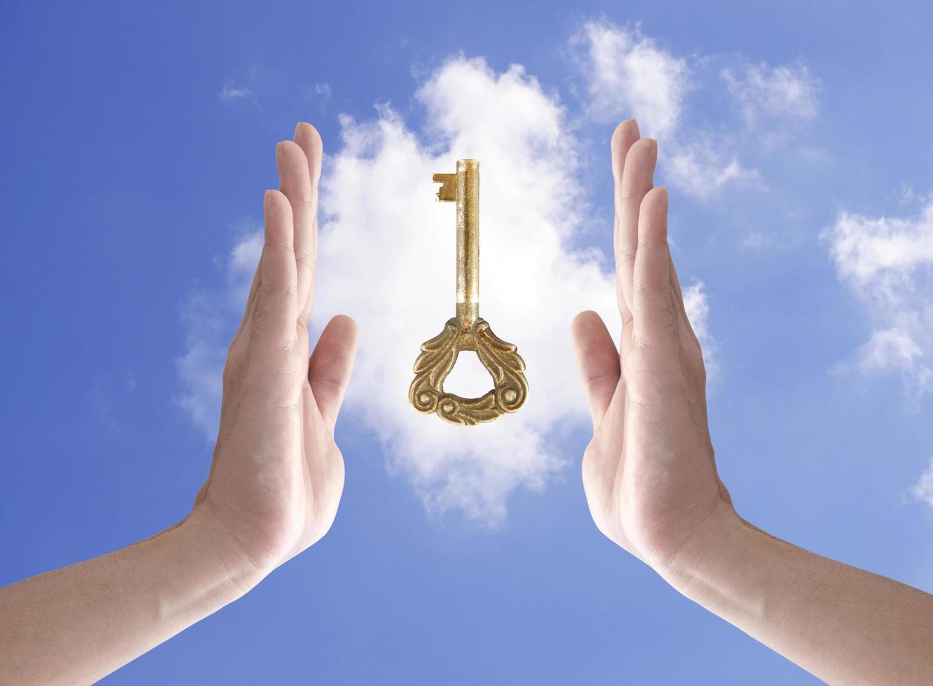 the key to success, hand holding key against blue sky photo