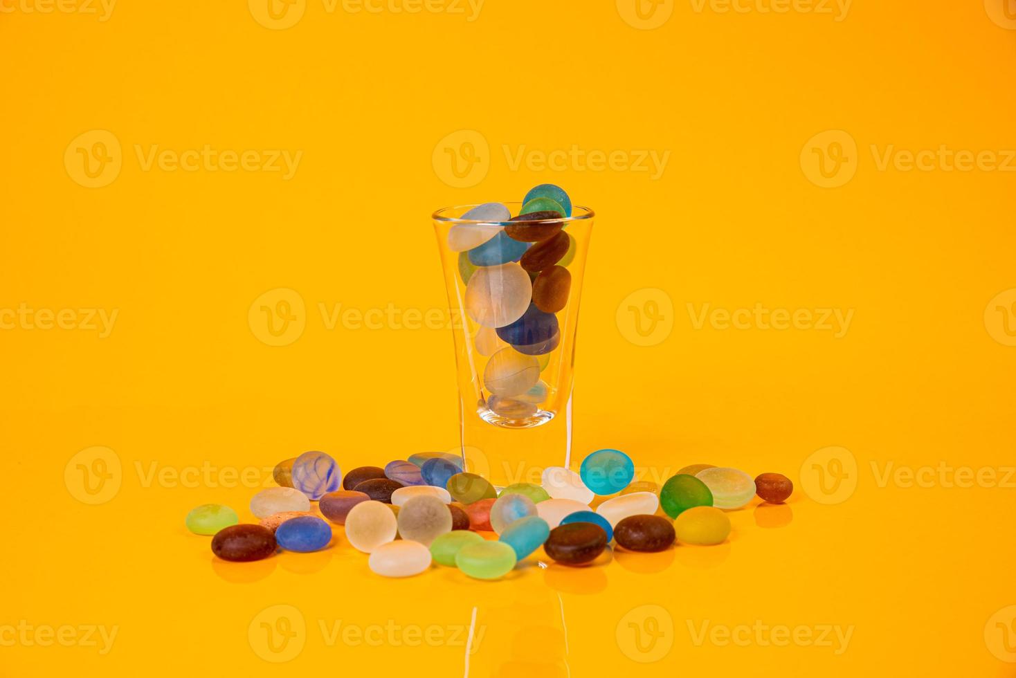 colored stones in glass in jar in bucket on orange background photo