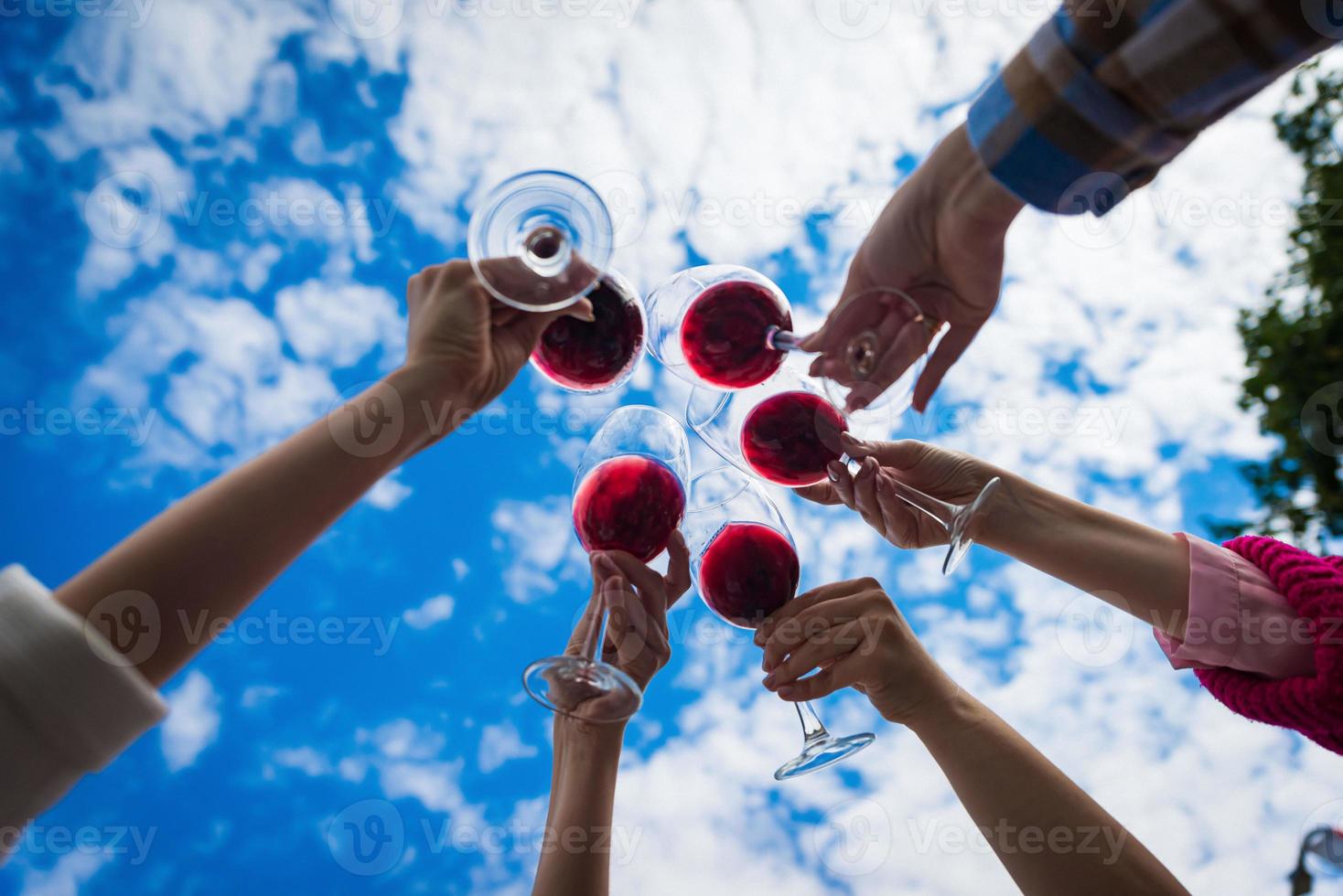 gente tintineando copas con vino en la terraza de verano de la cafetería o restaurante foto