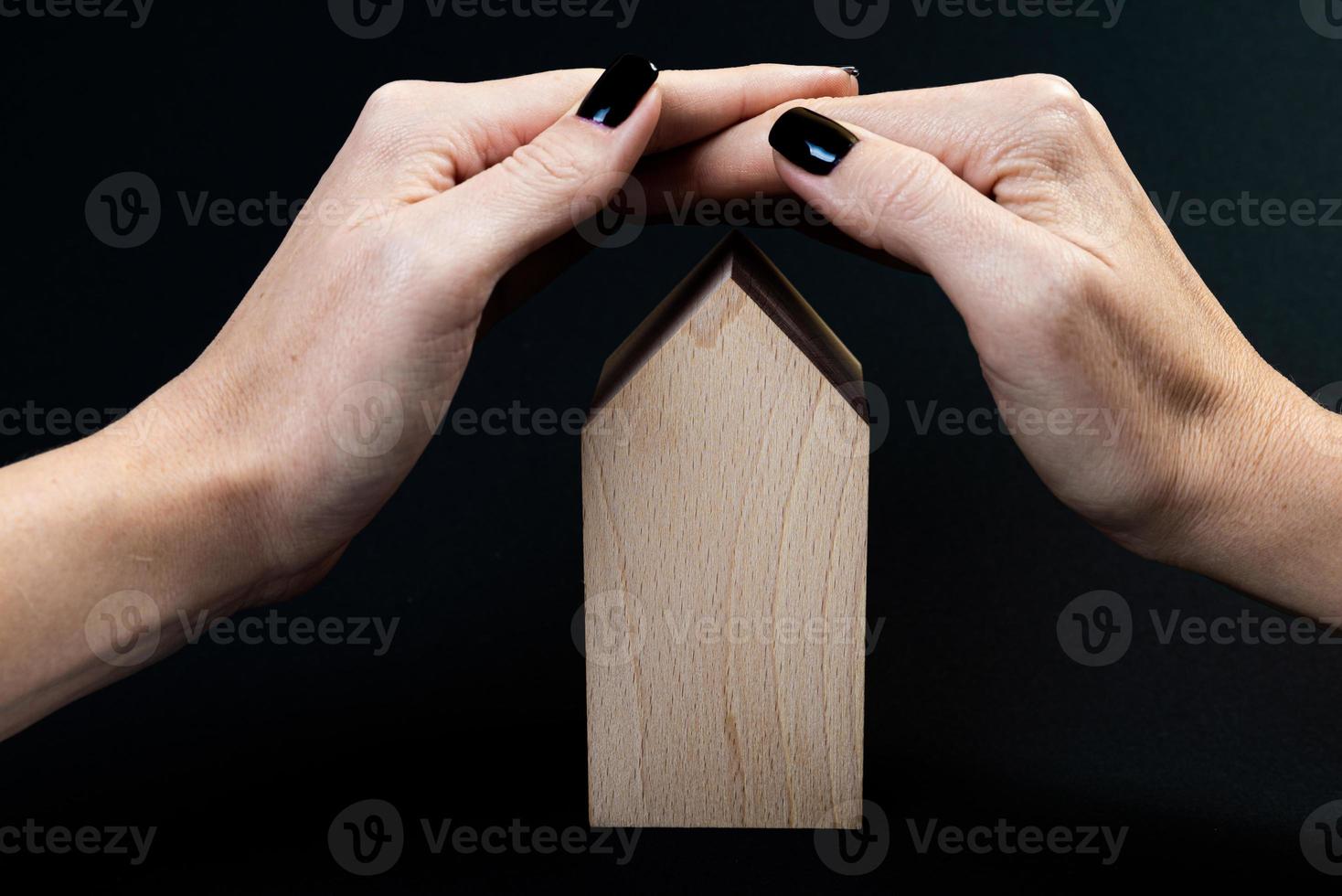Houses symbol Hand with metal key on black background. Real estate, insurance concept, mortgage, buy sell house, realtor concept, little cars, trees photo