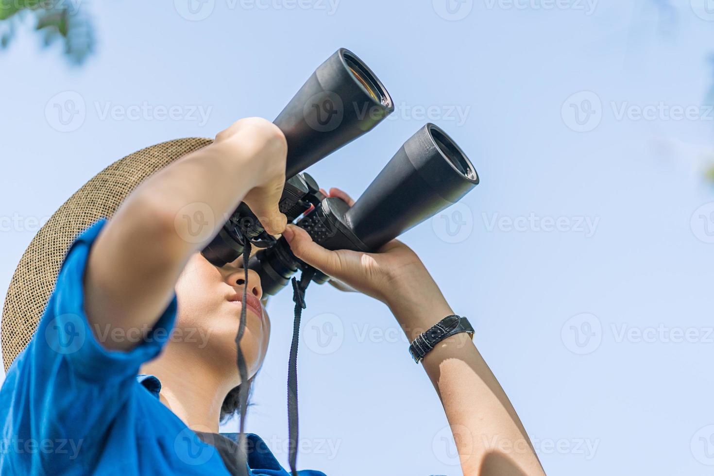 Close up Woman wear hat and hold binocular in grass field photo