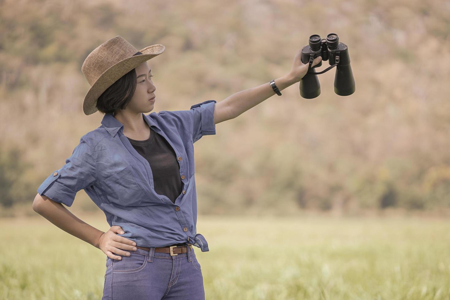 Woman wear hat and hold binocular in grass field photo