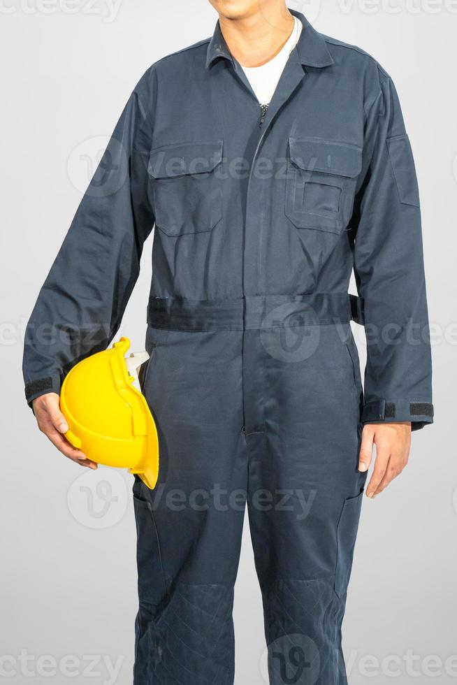 Worker standing in blue coverall holding hardhat photo