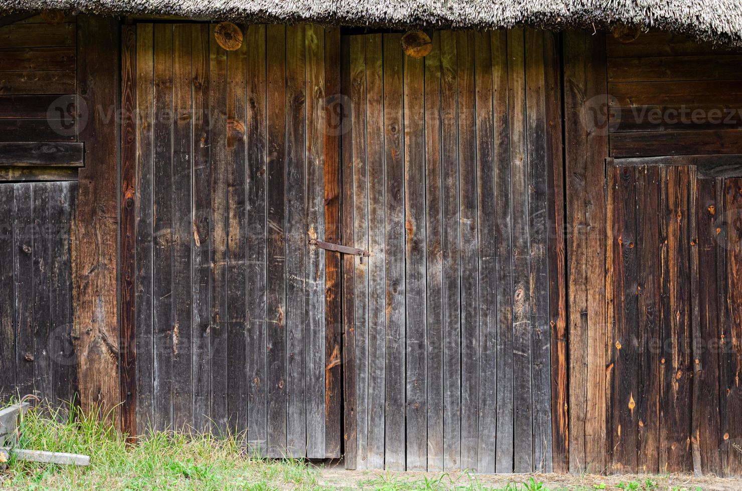 old weathered door in the wooden wall of an ancient hut photo