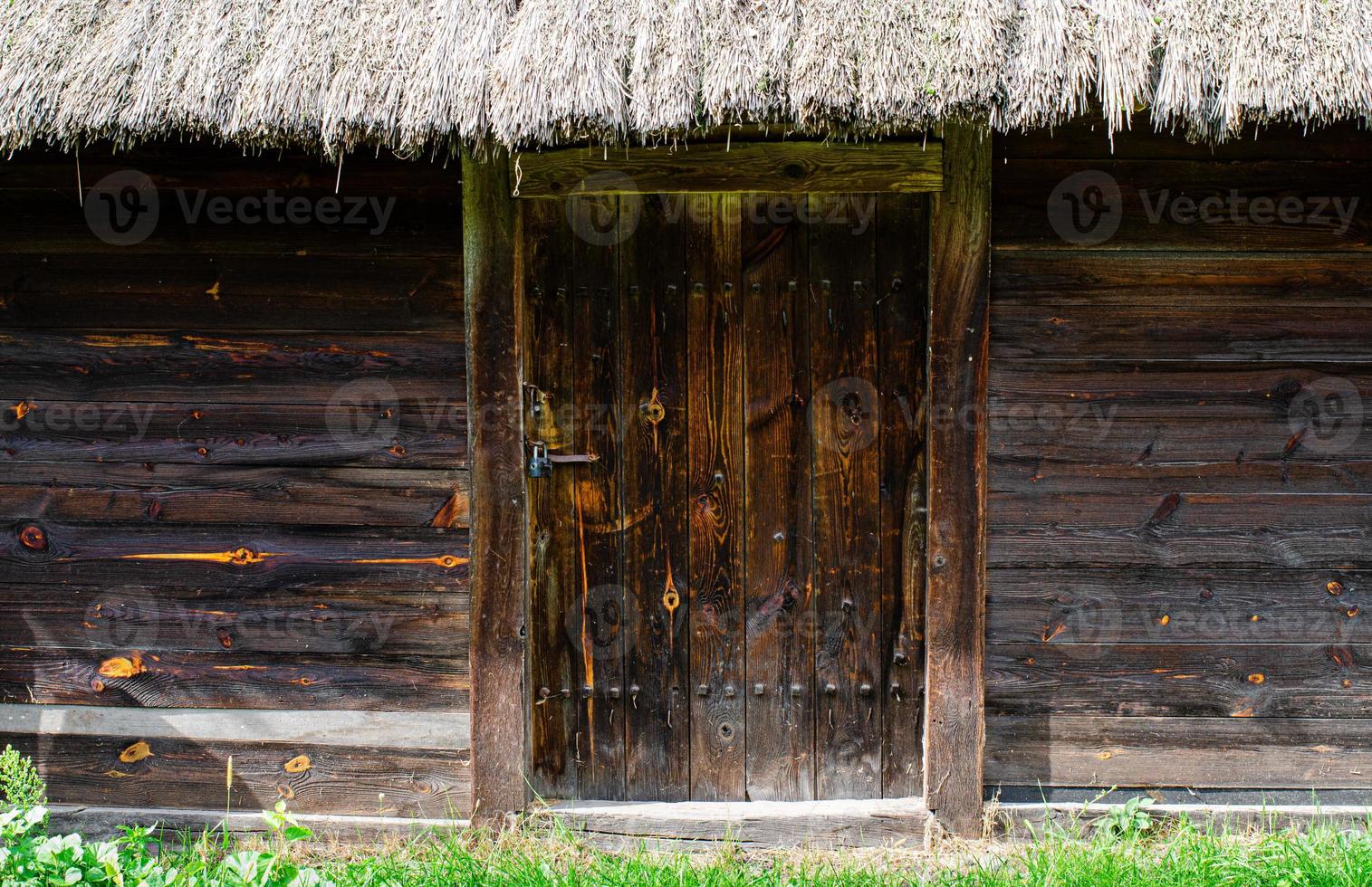 old weathered door in the wooden wall of an ancient hut photo